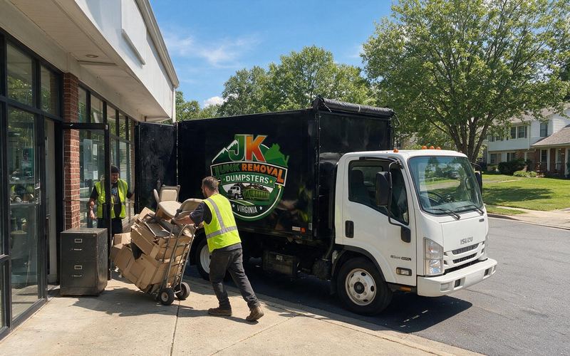 JK crew wheeling boxes and an office chair out of a storefront into the truck