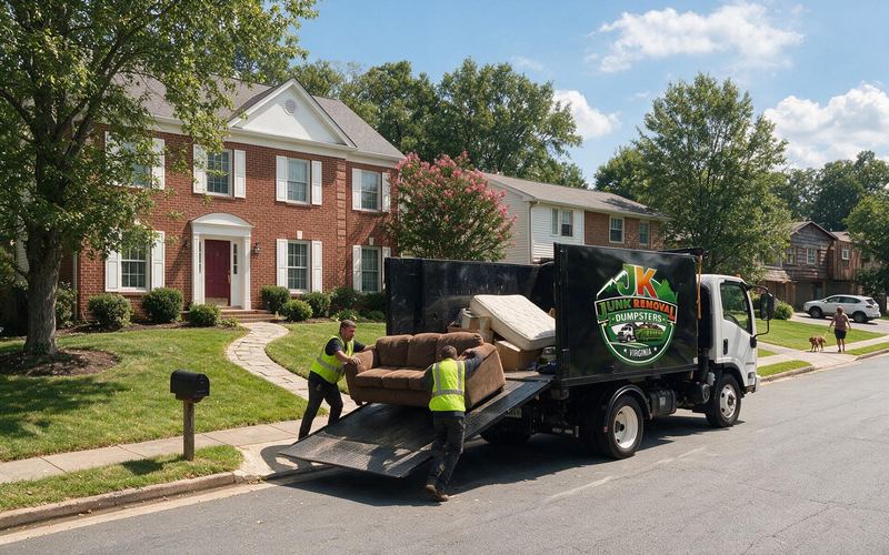 JK crew loading a sofa and a mattress into the black dump truck at a brick colonial home in Northern Virginia